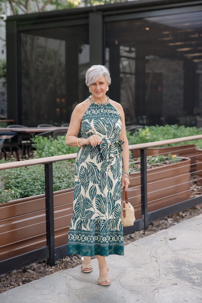 Green halter dress at dinner, golden hour. ALT: “Green palm-print halter dress — evening resort wear for women over 50