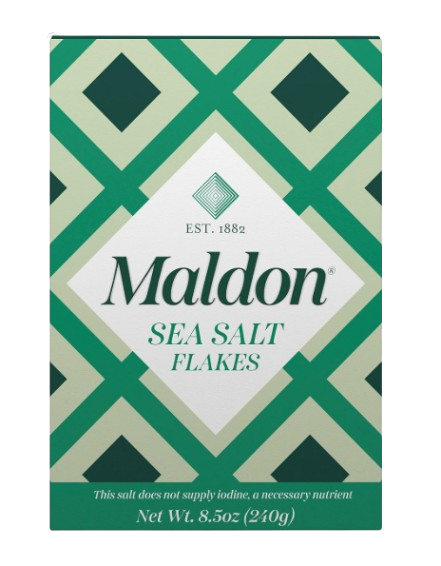 Green and white box of Maldon sea salt flakes with a geometric pattern, labeled with brand name and net weight on the front.