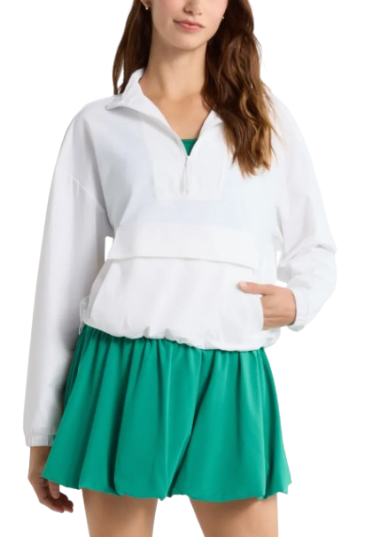Zella Transit Pullover Jacket in white featuring a half-zip neckline, stand collar, long sleeves, relaxed fit, and front pocket styled over a green athletic dress.