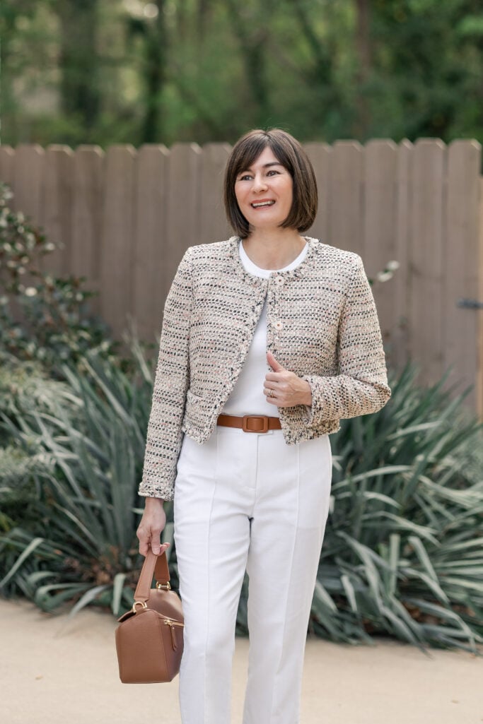 Kelly in three-quarter length shot wearing cream tweed lady jacket over white tee with cognac belt and leather bag — petite spring polished outfit