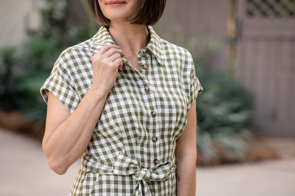 Close-up of olive gingham linen playsuit bodice showing collar, button-up front, and cap sleeves — petite romper styling detail