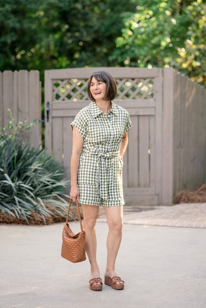 Kelly in full-length petite summer outfit featuring olive gingham linen playsuit with tie waist, cognac woven shoulder bag, and raffia platform espadrilles