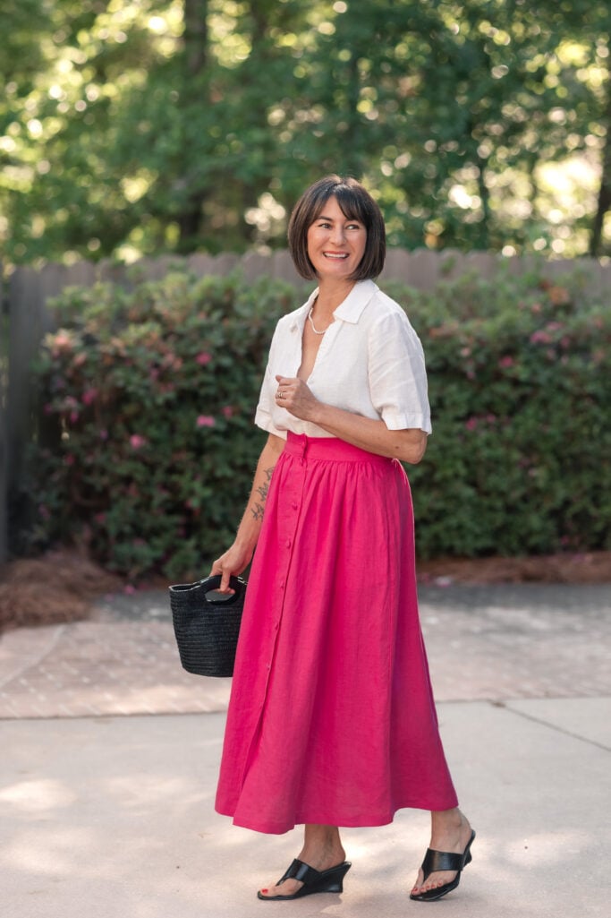 Side profile of Kelly in white linen popover tucked into hot pink button-front linen maxi skirt — petite summer outfit