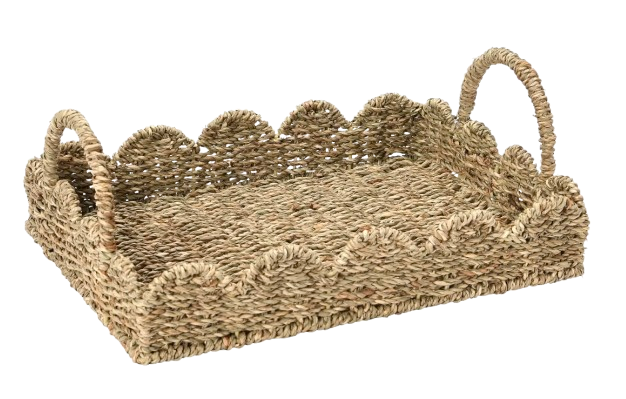 Natural woven seagrass serving tray with scalloped edges and curved handles, designed for casual entertaining, coffee table styling, or serving drinks outdoors.
