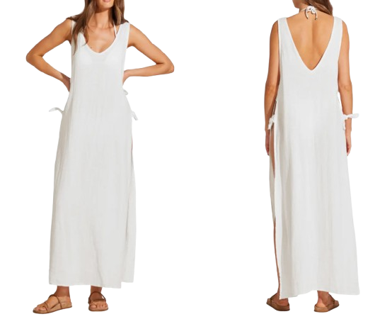 White sleeveless linen and cotton maxi cover-up dress with deep scoop neckline, side slits, and tie accents paired with flat sandals.