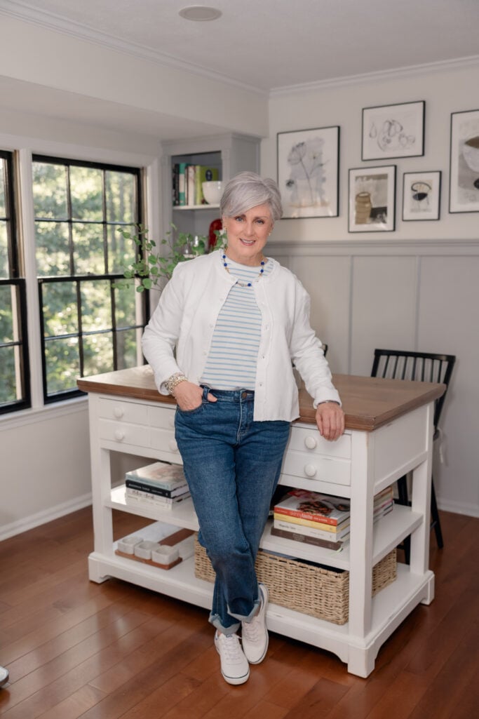 Beth of Style at a Certain Age in a white sweatshirt cardigan, striped tee, and slim jeans on unpacking day — apartment living after 60