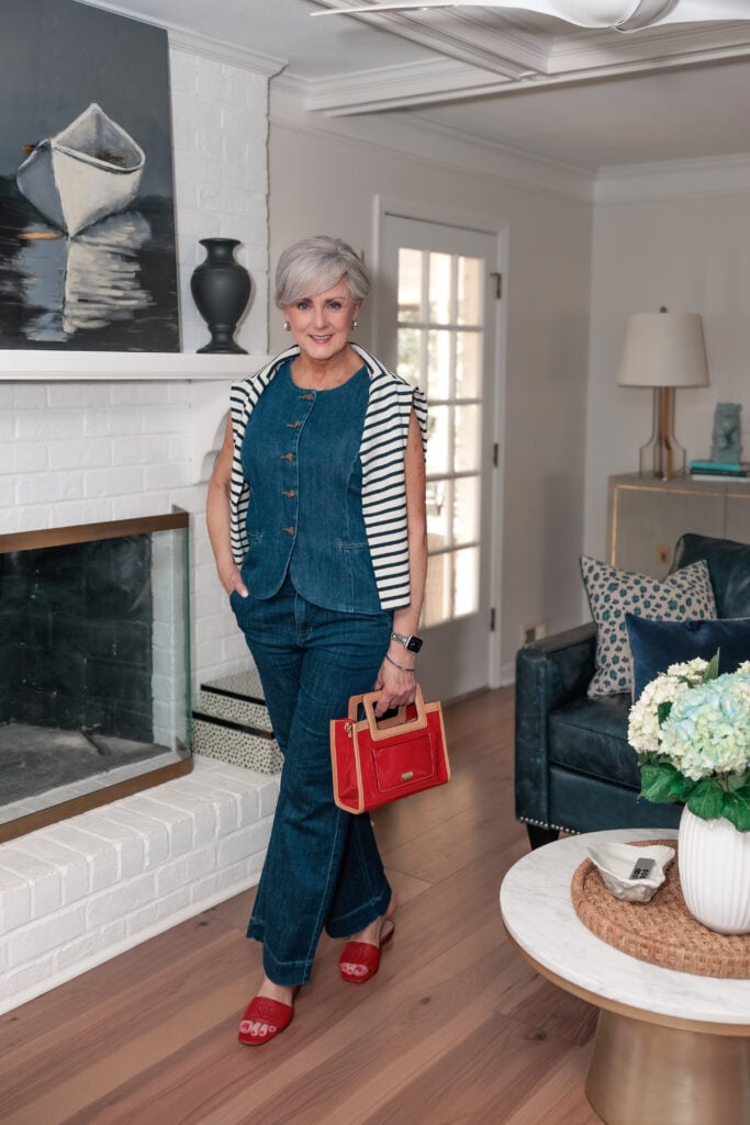 Denim vest and trouser jeans styled with striped sweater jacket, red sandals and red handbag for polished Americana outfit