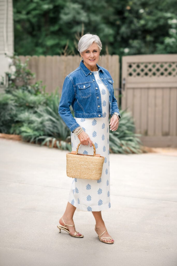 A woman with gray hair wearing a midi dress and denim jacket