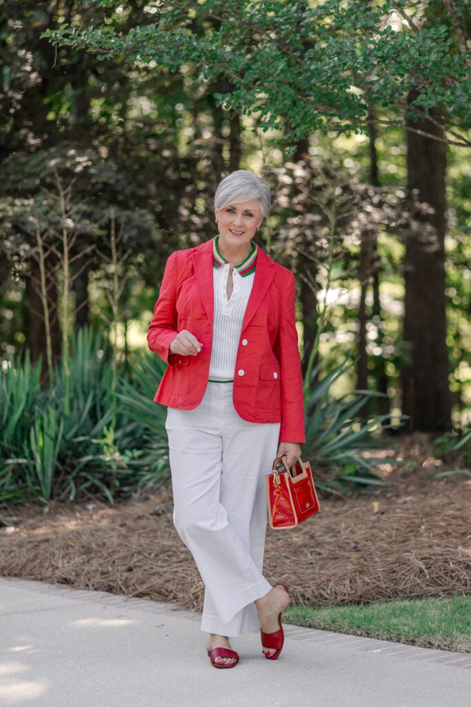Americana fashion trend over 50 with red linen blazer, striped polo, white wide-leg pants, red sandals and red handbag