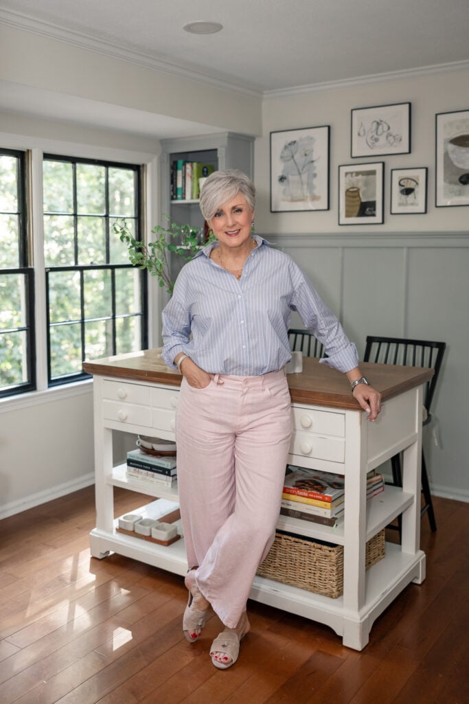 Beth of Style at a Certain Age in a striped shirt and pink linen pants while furnishing a new apartment in Atlanta