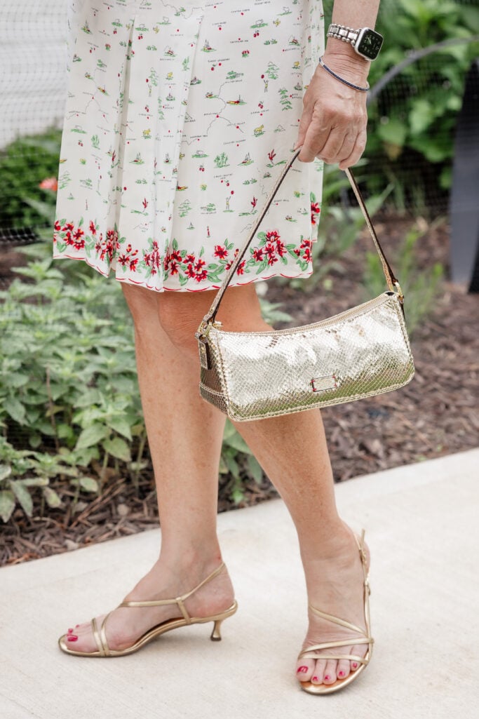 Beth Djalali wearing a white floral skirt set with gold strappy sandals and metallic handbag