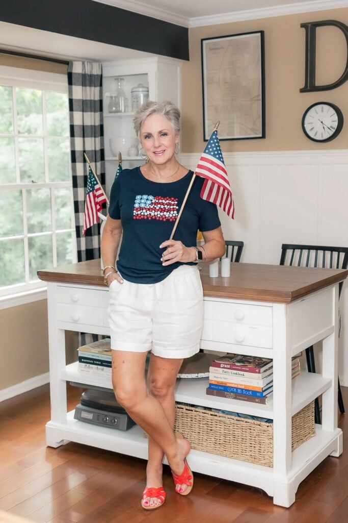 Flag tee outfit for women over 50 with white linen shorts, red slide sandals and patriotic summer style