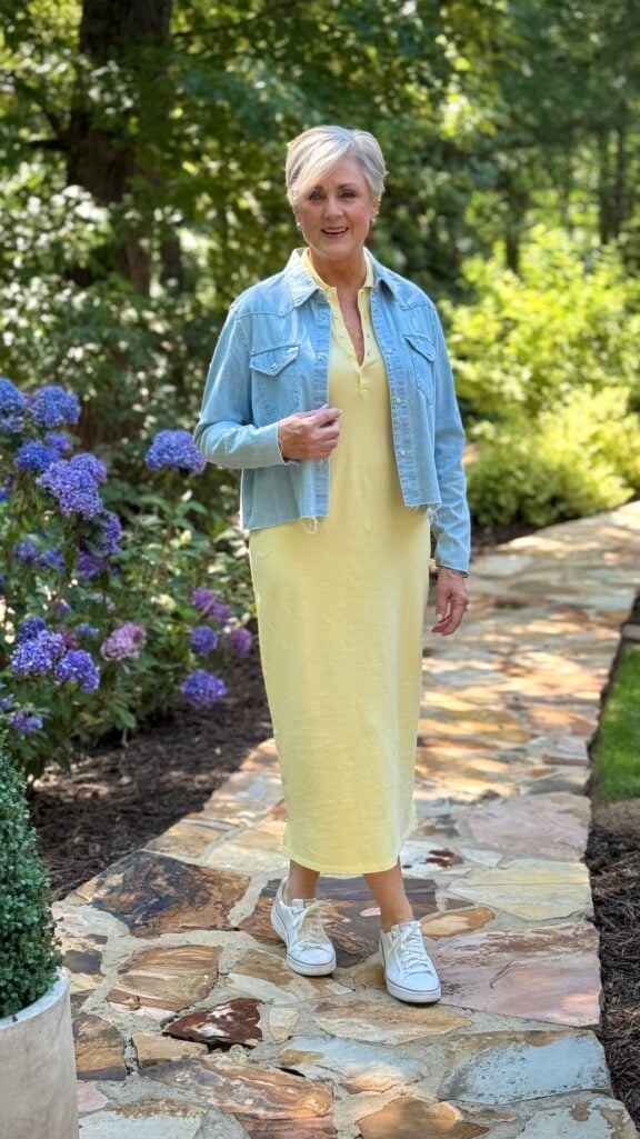 Knit midi dress layered with a dark rinse denim jacket and white leather sneakers for an easy travel day