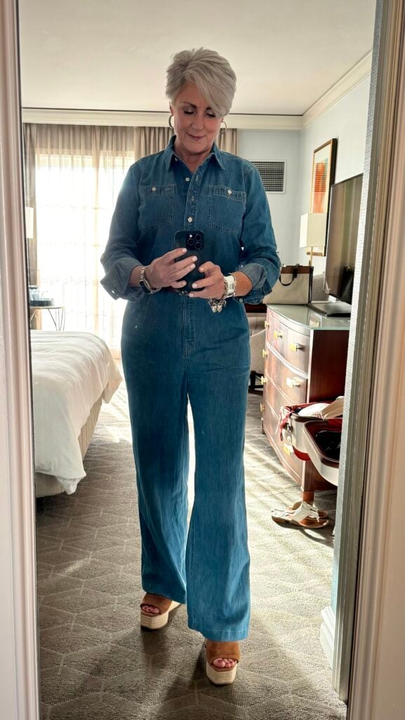 Denim jumpsuit styled for women over 50 with platform espadrilles and silver jewelry.