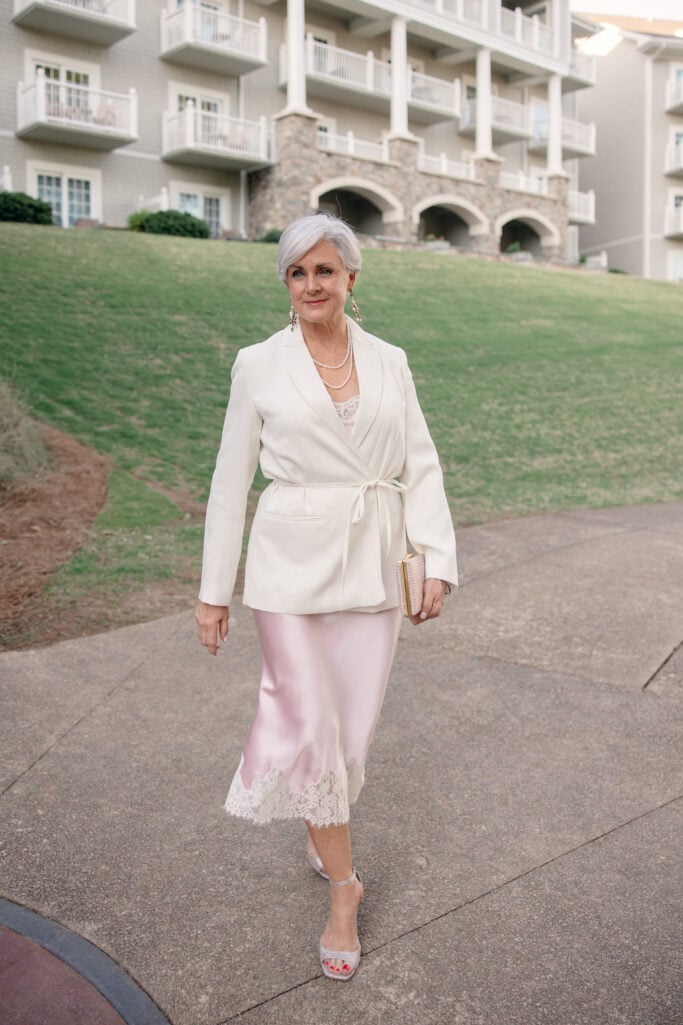BETH FROM STYLE AT A CERTAIN AGE WEARING A LACE CAMISOLE, SLIP SKIRT AND BELTED BLAZER