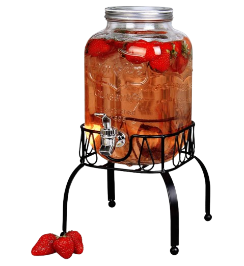 Glass beverage dispenser filled with strawberry-infused pink drink, featuring a metal spigot and decorative black stand, with fresh strawberries displayed at the base.