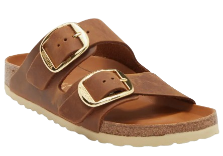 Cognac leather Birkenstock Arizona slide sandal featuring oversized gold-tone buckles, a contoured cork footbed, and a classic double-strap design.