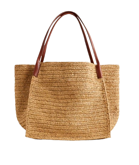 Large handknotted straw tote with rich brown leather shoulder straps, a relaxed woven texture, and an oversized shape ideal for beach days and travel.
