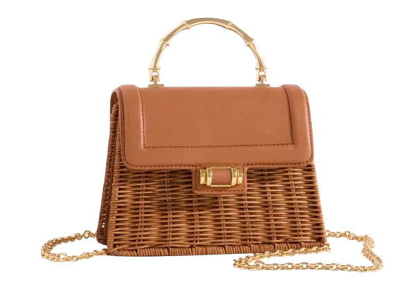 Structured wicker handbag with a warm brown woven body, smooth leather flap closure, bamboo-inspired top handle, and delicate gold chain strap.
