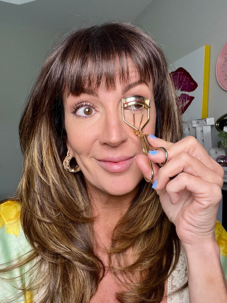 Hand holding a Shiseido eyelash curler to lift lashes after 50