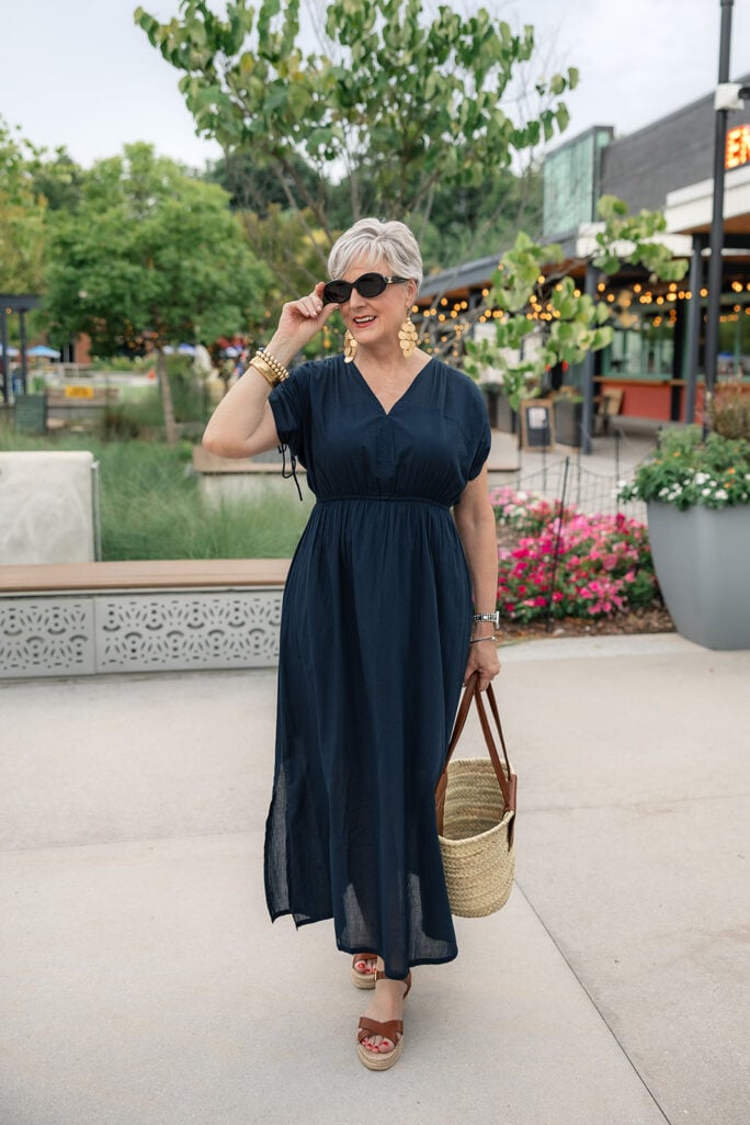 Beth Djalali in a navy V-neck maxi dress with gold coin earrings — an open neckline framing the face