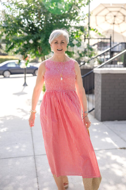 Beth Djalali laughing in a red gingham cotton midi dress and platform espadrilles — building a summer wardrobe for women over 50.
