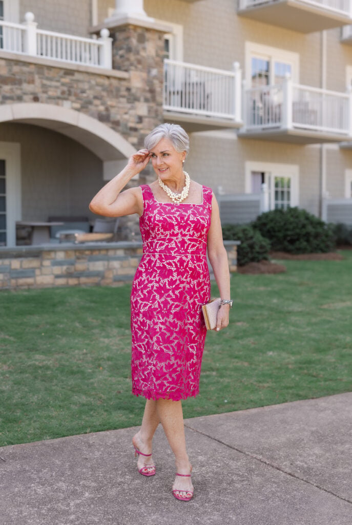 Beth wearing a fuchsia pink lace sheath dress with a layered pearl necklace and pink heeled sandals