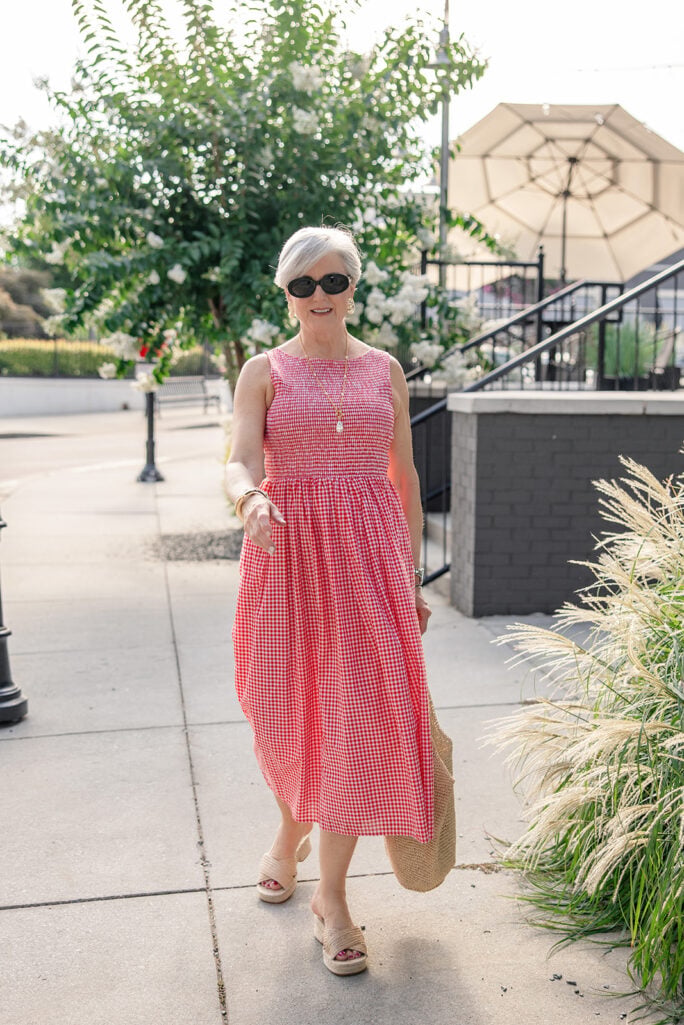 Woman wearing a red and white gingham midi dress with woven wedge sandals