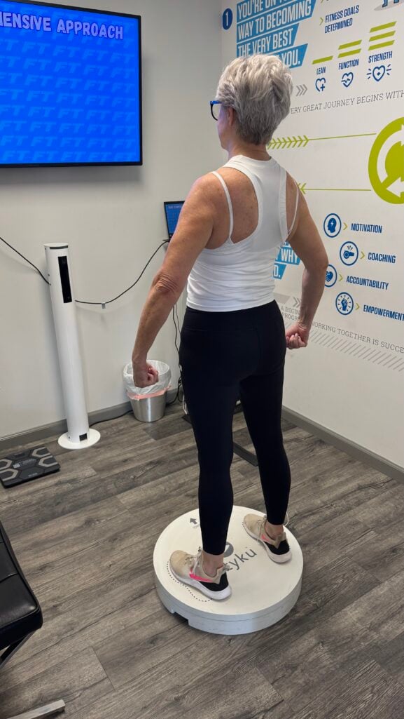 Beth Djalali standing on a Styku 3D body scanner at Fitness Together in Dunwoody, wearing a white tank top and black leggings