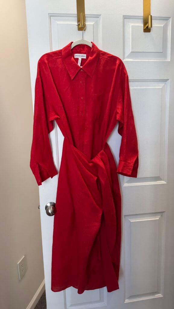 Silver-haired woman wearing a belted red linen shirtdress styled with cork wedges and a woven bag — casual daytime reunion outfit for women over 50.