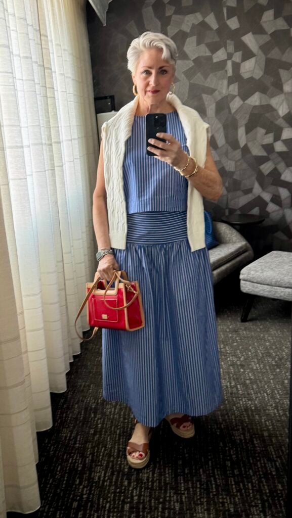 Woman over 50 in a blue-and-white striped skirt set with espadrilles and a red bag — a daytime reunion outfit idea.