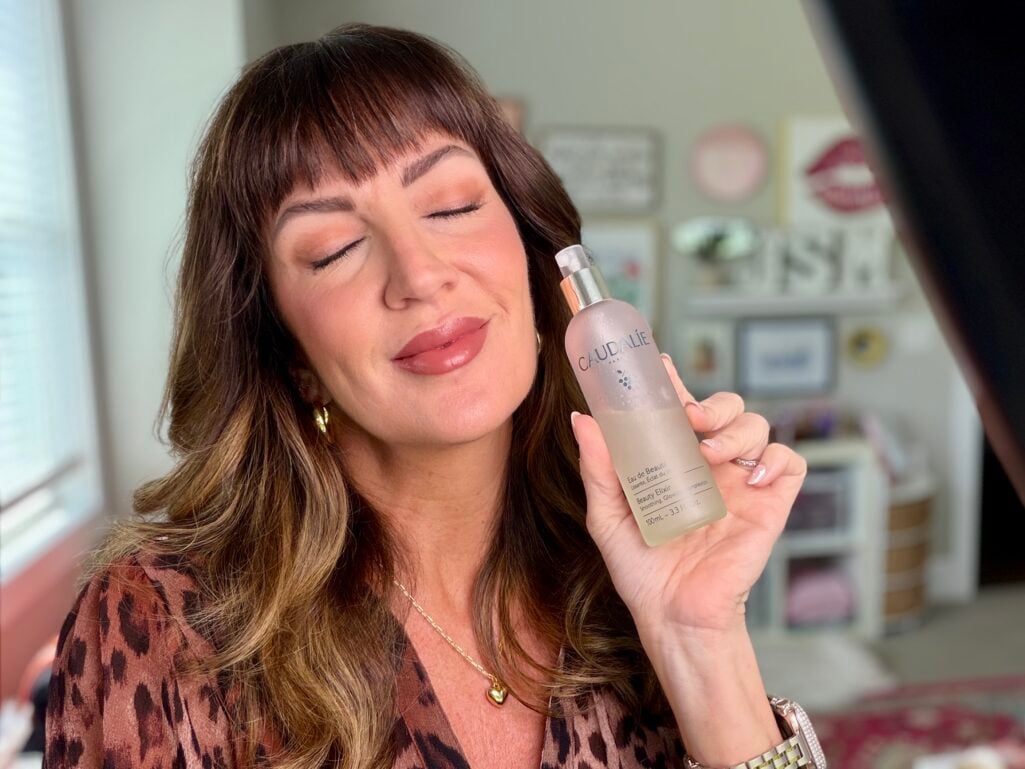 Misting Caudalie Beauty Elixir over the face to set makeup
