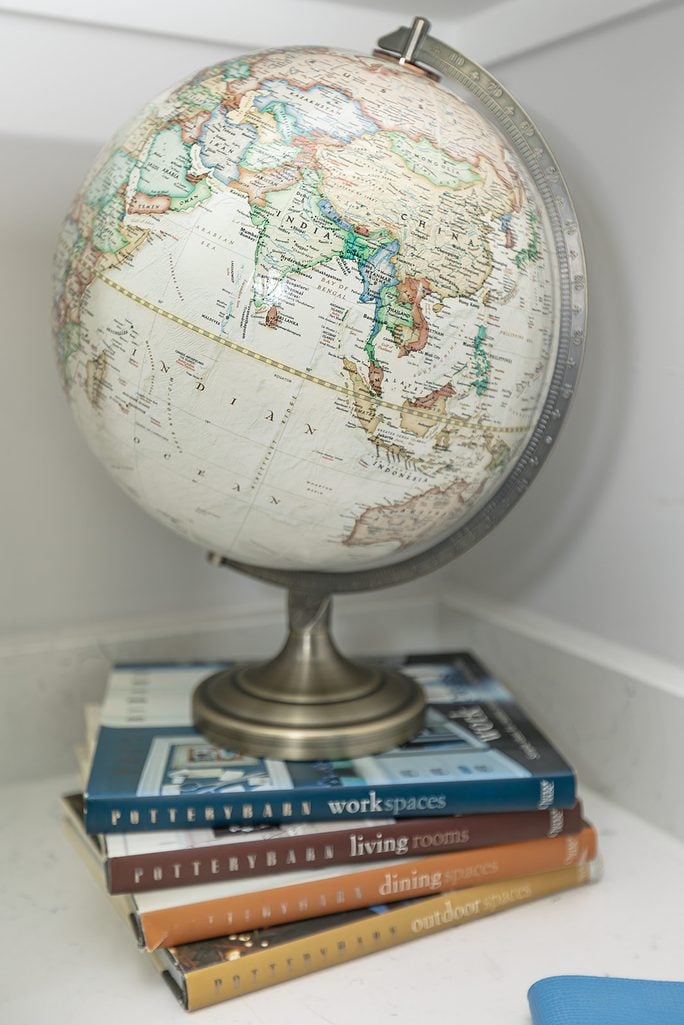 vintage-style globe, and stacked design books on a white quartz desk