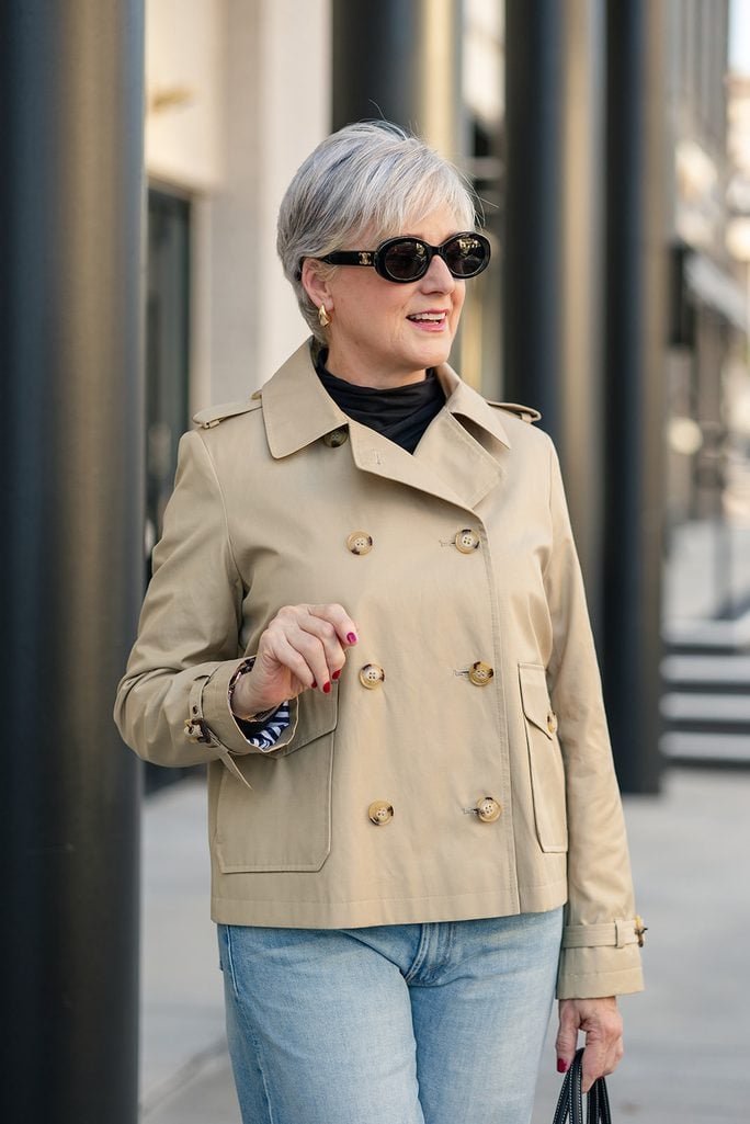 Beth wearing a cropped khaki trench coat with classic trench details