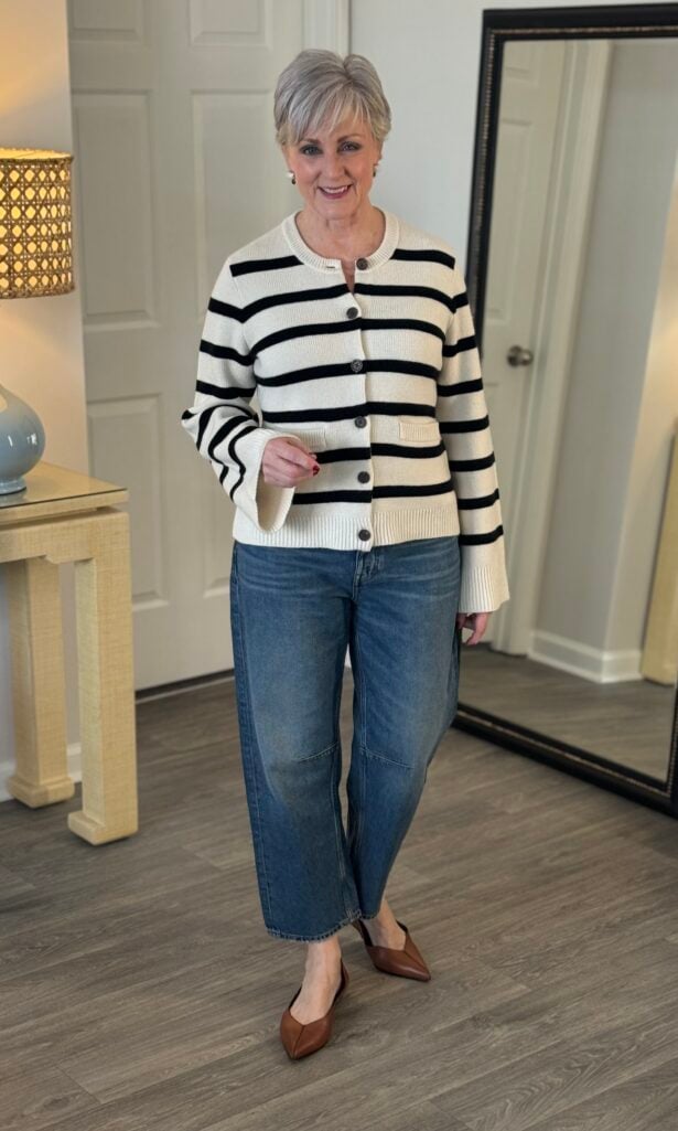 Barrel jeans, side view showing the curved leg, with a striped cardigan and flats.