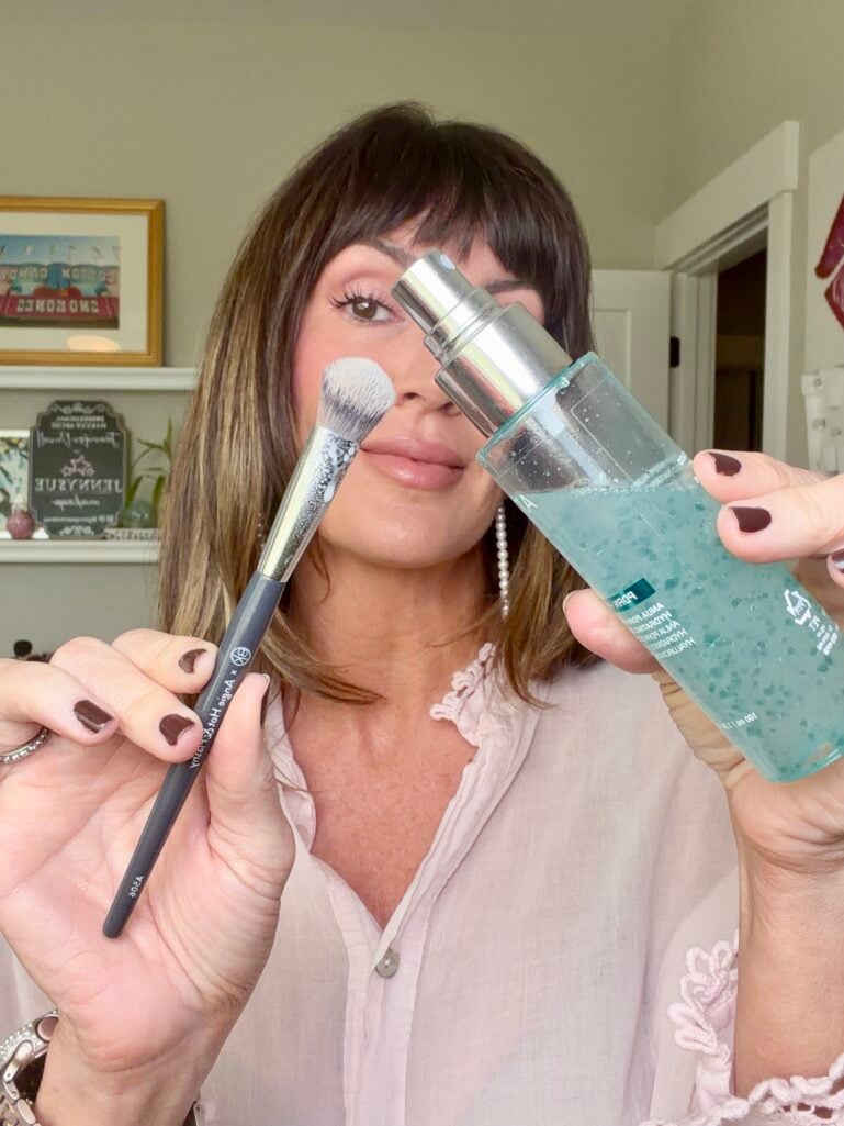 Spraying the concealer brush with Anua mist before stippling
