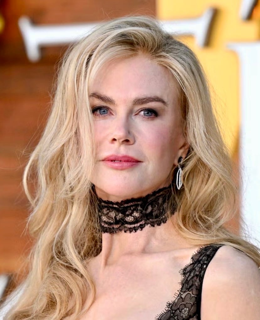 Close-up of Nicole Kidman with loose blonde waves, a black lace choker, soft brown eyeshadow, full brows, and a rosy pink lip