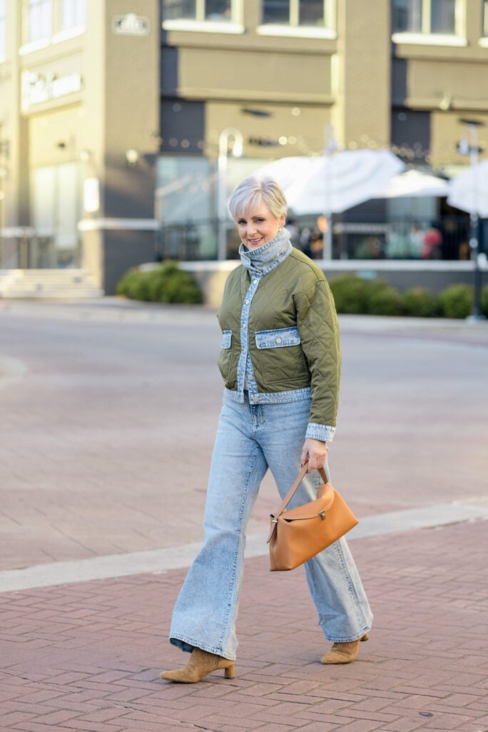 Beth Djalali laughing in an olive quilted jacket with acid-wash denim collar, cuffs and pockets, and silver earrings