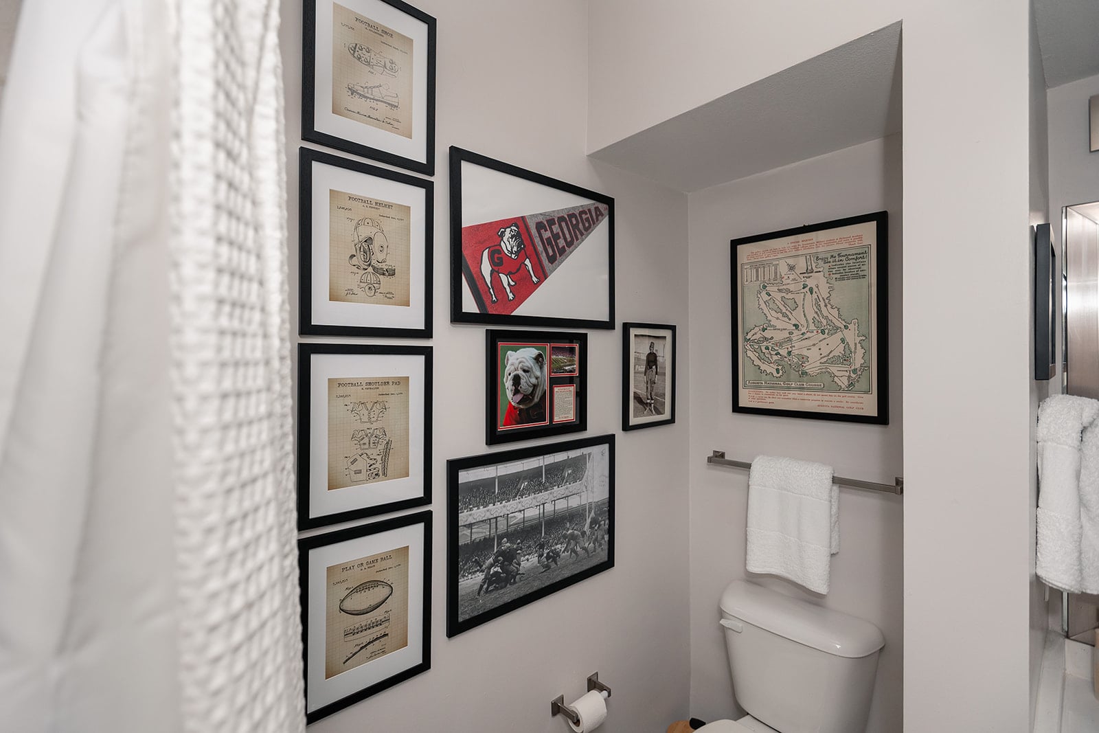 Ralph Lauren–inspired guest bathroom with vintage sports photographs hung salon-style from floor to ceiling