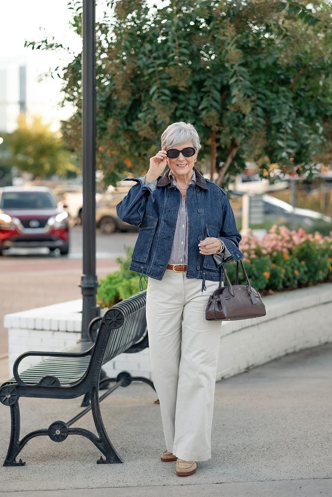Fall weekend outfits — Beth in a denim jacket with corduroy collar, navy gingham shirt, cream wide-leg chinos, tan suede loafers, and black oval sunglasses.