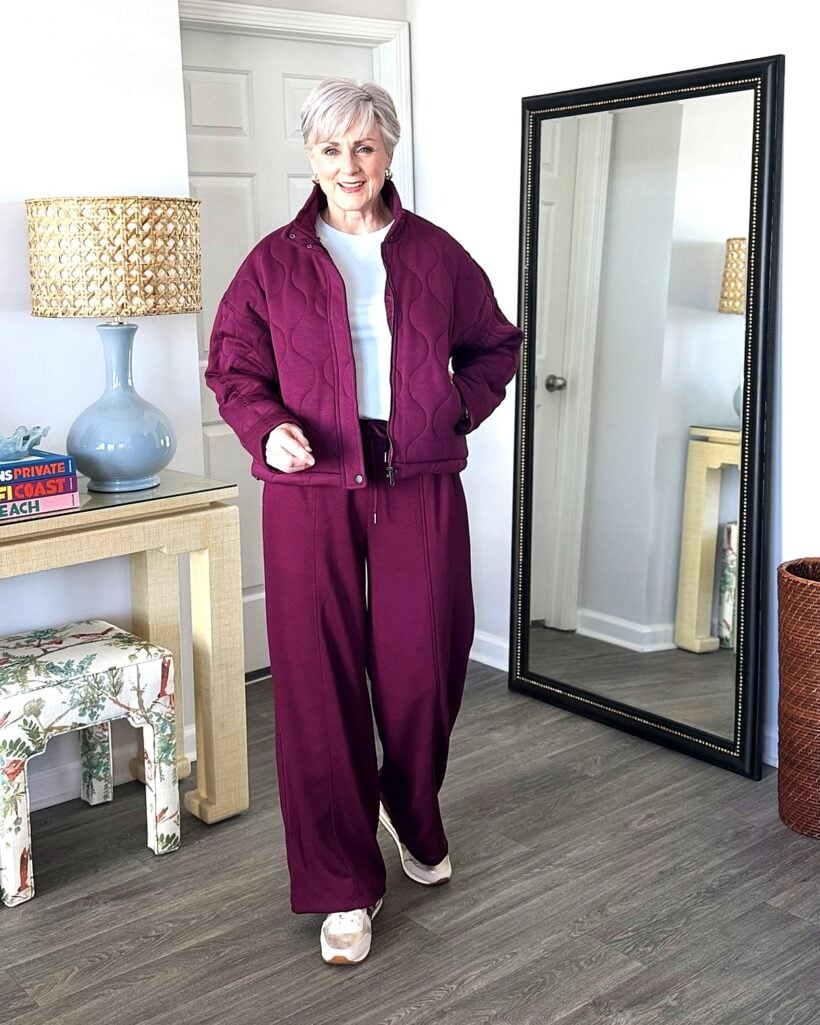 Beth in plum quilted jacket and wide-leg pants, blue tee, metallic sneakers
