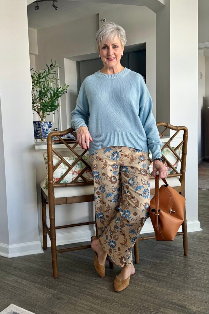 Beth in blue crewneck sweater, patterned pants and mules