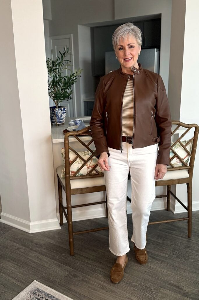 Leather jacket with a striped tee and white jeans; close-up: collar snap and buckle tab detail